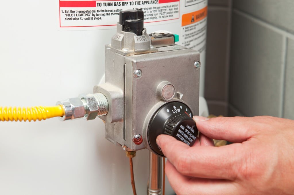 62e62c4e4b1e8 "A male hand is turning down the temperature on a gas water heater's thermostat. This is a measure of energy conservation which requires less gas to be consumed heating the stored water. Additionally, this could serve as a home safety image, by turning down the temperature the risk of scalding is reduced."